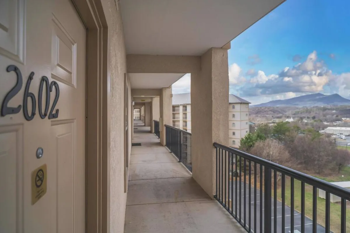 A private balcony featuring a sturdy railing and a sweeping view of the mountains. The tranquil scene invites residents to relax outdoors, soak in the beauty of the Smoky Mountains, and fully experience the peaceful, park-like ambiance from their own home.