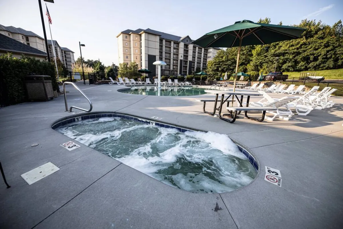 This inviting exterior scene features a hot tub and swimming pool bordered by lounge chairs and a picnic table, ideal for group gatherings. The relaxed vibes and multi-use outdoor space are well-suited for family socializing and barbecues.