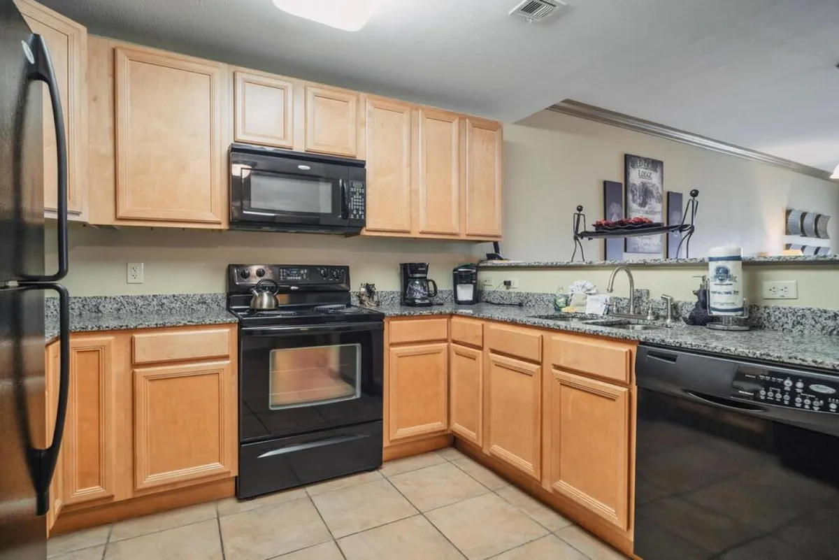 A close-up of the kitchen area with granite countertops, stainless steel appliances, and light wood cabinetry. The workspace is well-lit and practical, showcasing where guests can blend smoothies, prepare breakfast, or cook a celebratory dinner with ease.