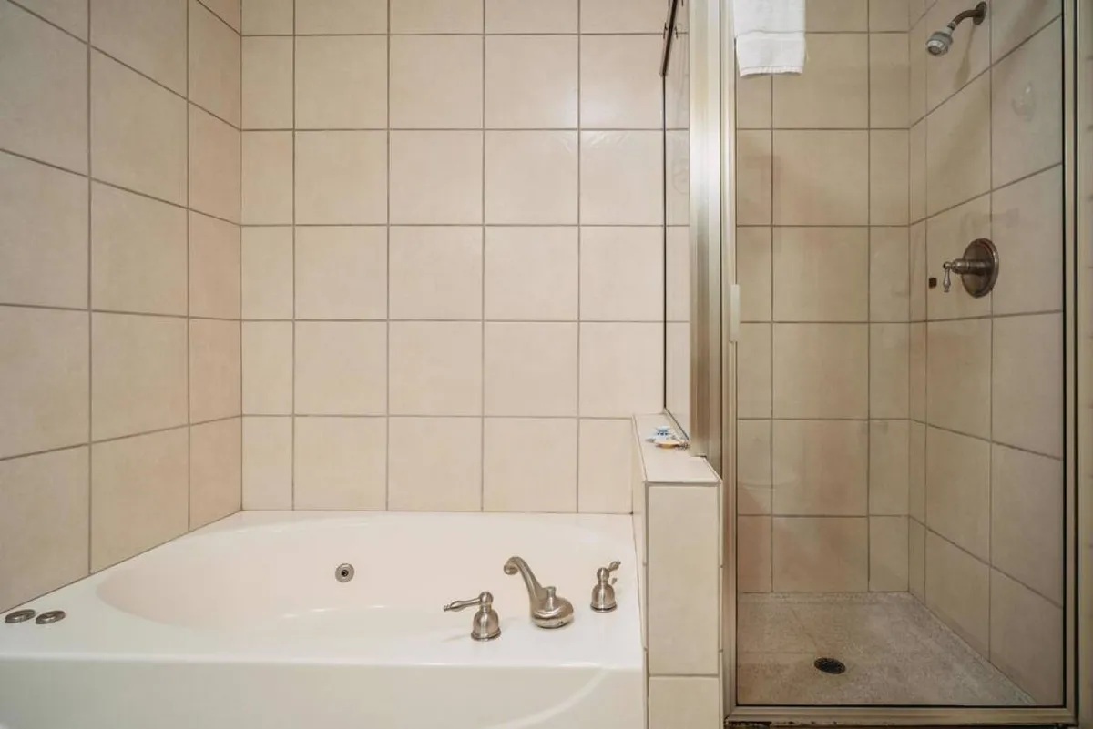 A serene bathroom scene with a bathtub and a separate shower area, surrounded by stylish tiles. The space feels tranquil and spa-like, ideal for relaxing baths or refreshing showers after a busy day.
